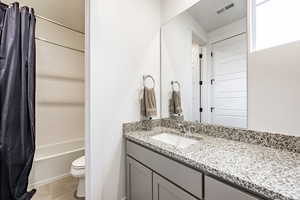 Full bathroom with toilet, bathtub / shower combination, vanity, and tile patterned flooring