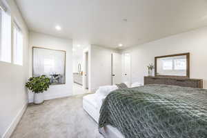 Bedroom featuring connected bathroom, light carpet, and multiple windows