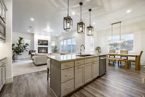 Kitchen with a center island with sink, dark wood-type flooring, pendant lighting, gray cabinets, and sink