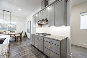 Kitchen with stainless steel gas stovetop, light stone countertops, and plenty of natural light