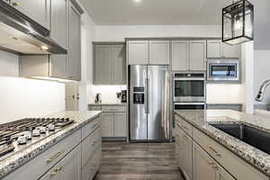 Kitchen featuring appliances with stainless steel finishes, dark hardwood / wood-style floors, pendant lighting, gray cabinetry, and sink