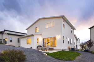 Back house at dusk with central air condition unit and a patio area