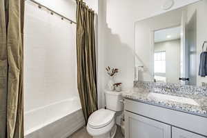 Full bathroom featuring vanity, toilet, and shower / bath combination with curtain