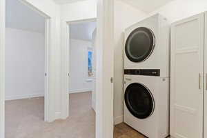 Clothes washing area with stacked washer and clothes dryer and light carpet