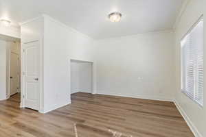 Empty room featuring wood-type flooring and crown molding