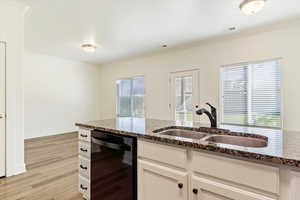 Kitchen featuring white cabinetry, plenty of natural light, and dark stone countertops