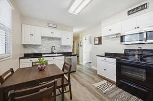 Kitchen featuring stainless steel appliances, light wood-style floors, white cabinets, and sink