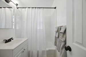 Bathroom featuring vanity and shower / bath combination with curtain