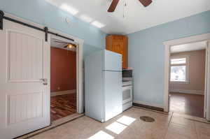 Kitchen featuring light wood-type flooring, a barn door, white appliances, and ceiling fan