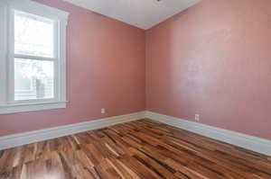 Empty room featuring dark wood-type flooring and ceiling fan