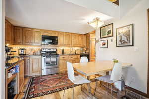 Kitchen with sink, black appliances, light hardwood / wood-style flooring, and tasteful backsplash