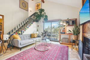 Living room with beamed ceiling, wood-type flooring, high vaulted ceiling, and ceiling fan