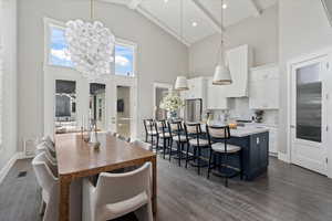 Dining room with beamed ceiling, high vaulted ceiling, a chandelier, and dark hardwood / wood-style flooring