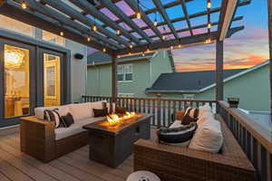 Deck at dusk featuring an outdoor living space with a fire pit and a pergola