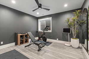 Exercise room with ceiling fan and light hardwood / wood-style flooring