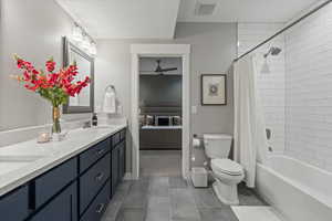 Full bathroom featuring tile patterned flooring, shower / tub combo, ceiling fan, vanity, and toilet