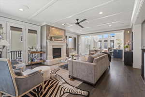 Living room with ceiling fan, dark hardwood / wood-style floors, and crown molding