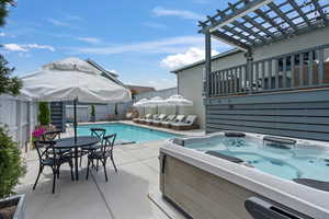 View of pool with a hot tub, a patio, and a pergola