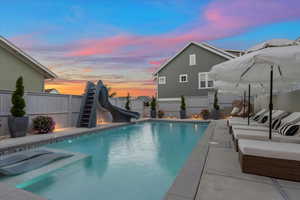 Pool at dusk featuring a patio area and a water slide