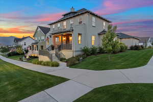 Property exterior at dusk featuring a porch and a yard