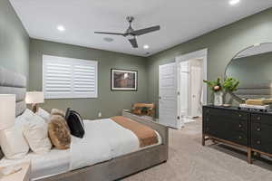 Bedroom with ensuite bathroom, light carpet, and ceiling fan