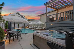 Patio terrace at dusk with a pool with hot tub and a pergola