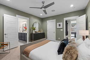 Bedroom featuring ceiling fan, connected bathroom, and light carpet