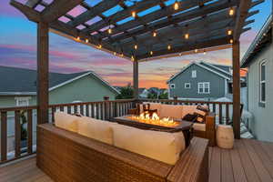 Deck at dusk with an outdoor living space with a fire pit and a pergola