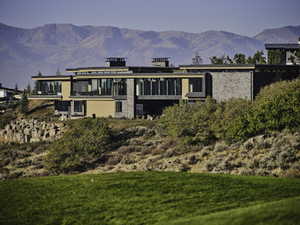 Back of property with a mountain view and a yard