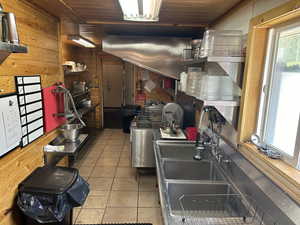 Kitchen with wooden walls, light tile patterned floors, wood ceiling, and sink