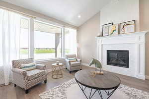 Living room with baseboards, visible vents, wood finished floors, and vaulted ceiling