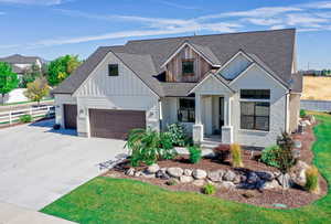 Modern farmhouse with a garage, fence, board and batten siding, and roof with shingles