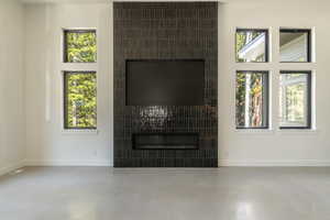 Unfurnished living room with finished concrete flooring, a fireplace, and plenty of natural light