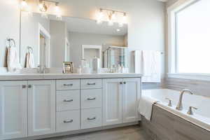 Bathroom featuring a bath, double vanity, a sink, and a stall shower