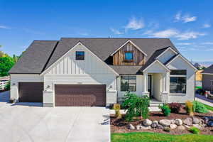 Modern farmhouse style home with driveway, a garage, board and batten siding, and roof with shingles
