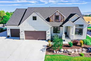 Modern inspired farmhouse with driveway, an attached garage, board and batten siding, and roof with shingles