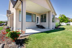 Exterior space with stucco siding, a shingled roof, a front lawn, and entry steps