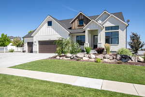 Modern farmhouse style home with driveway, fence, board and batten siding, a front lawn, and a shingled roof