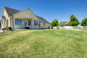 Exterior space with a lawn, a shingled roof, fence, and entry steps