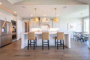 Kitchen with dark wood-style flooring, light countertops, stainless steel appliances, and tasteful backsplash