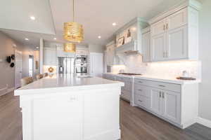 Kitchen with tasteful backsplash, wood finished floors, light countertops, and appliances with stainless steel finishes