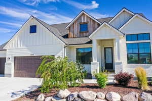 Modern farmhouse style home featuring an attached garage, board and batten siding, concrete driveway, and roof with shingles