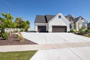 Modern farmhouse featuring driveway, an attached garage, fence, and board and batten siding