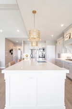 Kitchen featuring light countertops, a spacious island, stainless steel appliances, and light wood-style floors