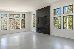 Unfurnished living room with baseboards, recessed lighting, a fireplace, and finished concrete floors