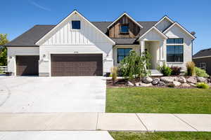 Modern farmhouse featuring a garage, concrete driveway, a front lawn, board and batten siding, and roof with shingles
