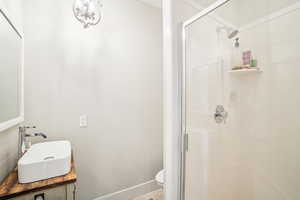 Bathroom featuring toilet, vanity, and a shower with door