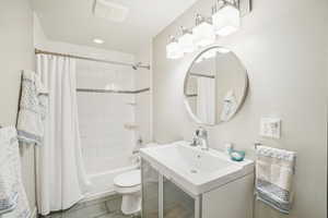 Full bathroom featuring tile patterned floors, vanity, toilet, and shower / bath combination with curtain