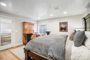 Bedroom with light hardwood / wood-style floors and a textured ceiling