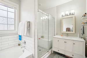 Bathroom featuring tile patterned flooring, vanity, and plus walk in shower